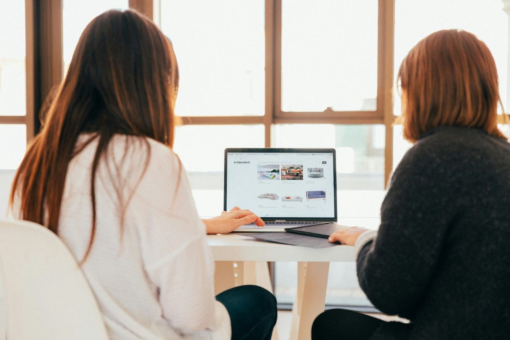 Two colleagues reviewing work on a laptop